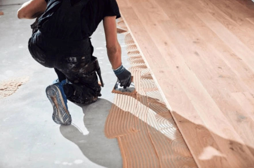 Installer fastening solid hardwood planks during a Norman floor installation