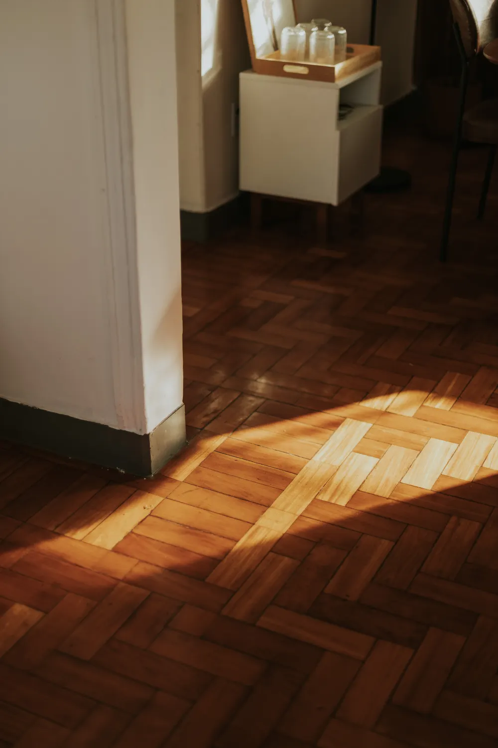 Herringbone wood flooring with lighter replacement blocks patched into the existing floor before staining