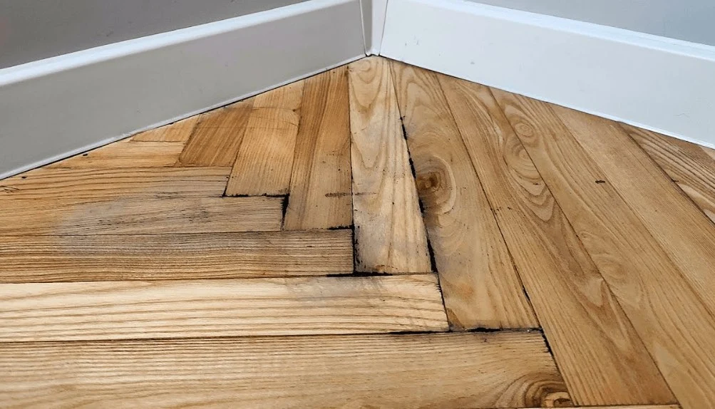 Cupped and buckled oak flooring from water damage awaiting board replacement